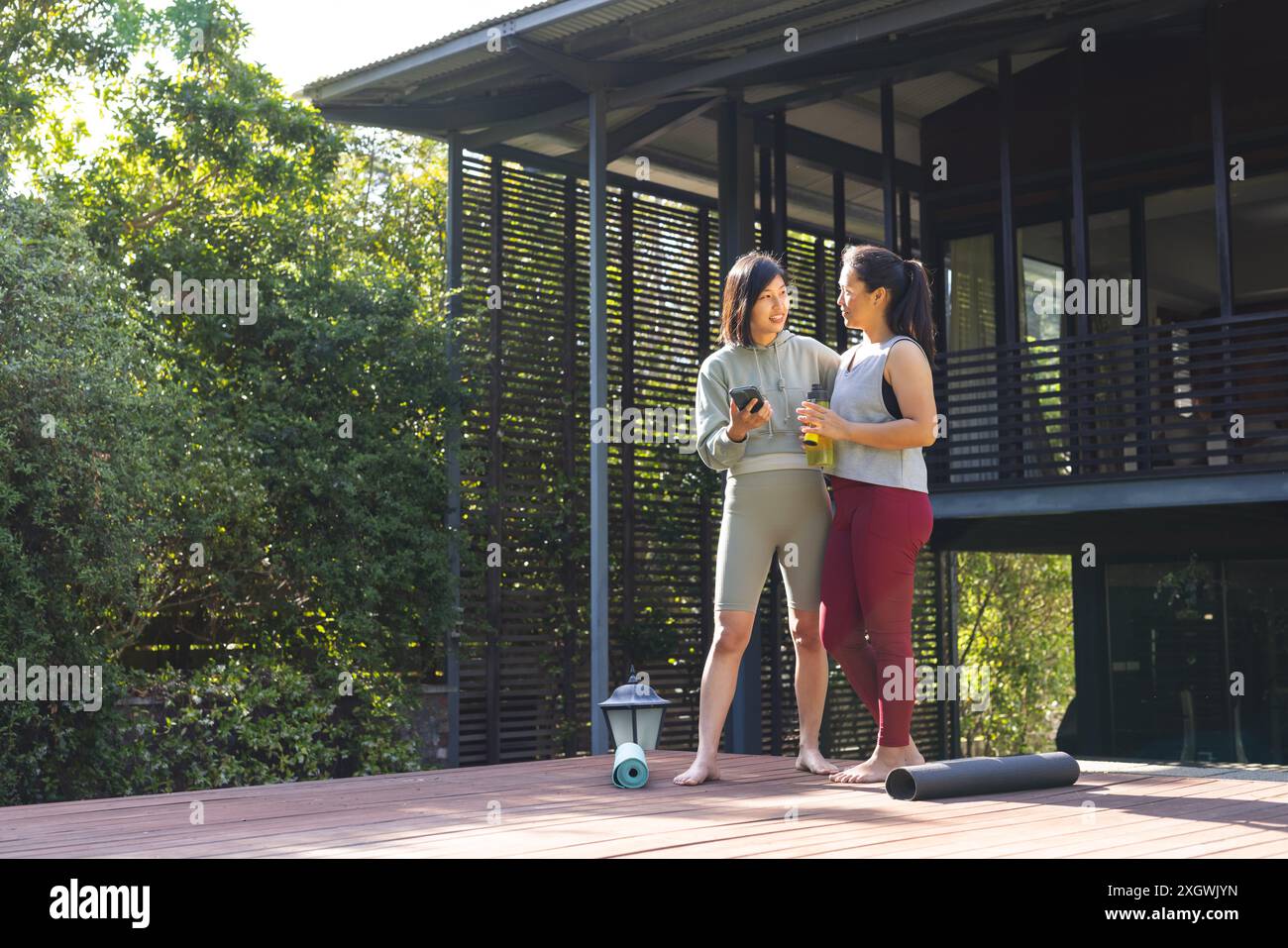 Unalt Happy asian female friends using smartphone and talking in garden at ...
