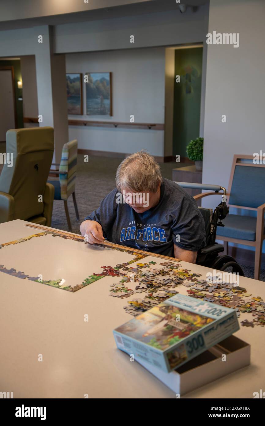 Maplewood, Minnesota. Elderly woman stroke victim working on a puzzle in the community room in a nursing home. Stock Photo