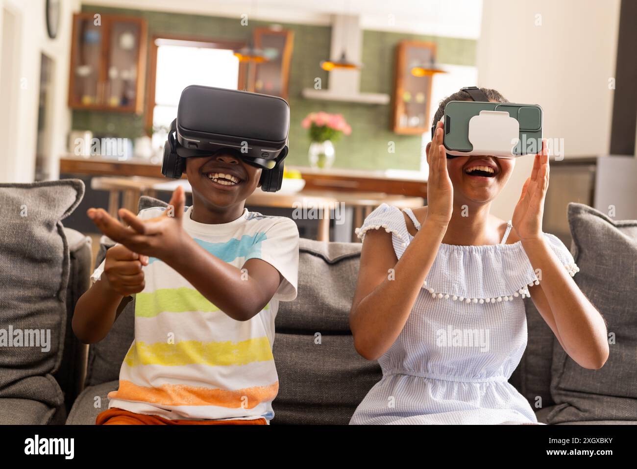 Teenage biracial brother and sister enjoy VR games at home. Their ...