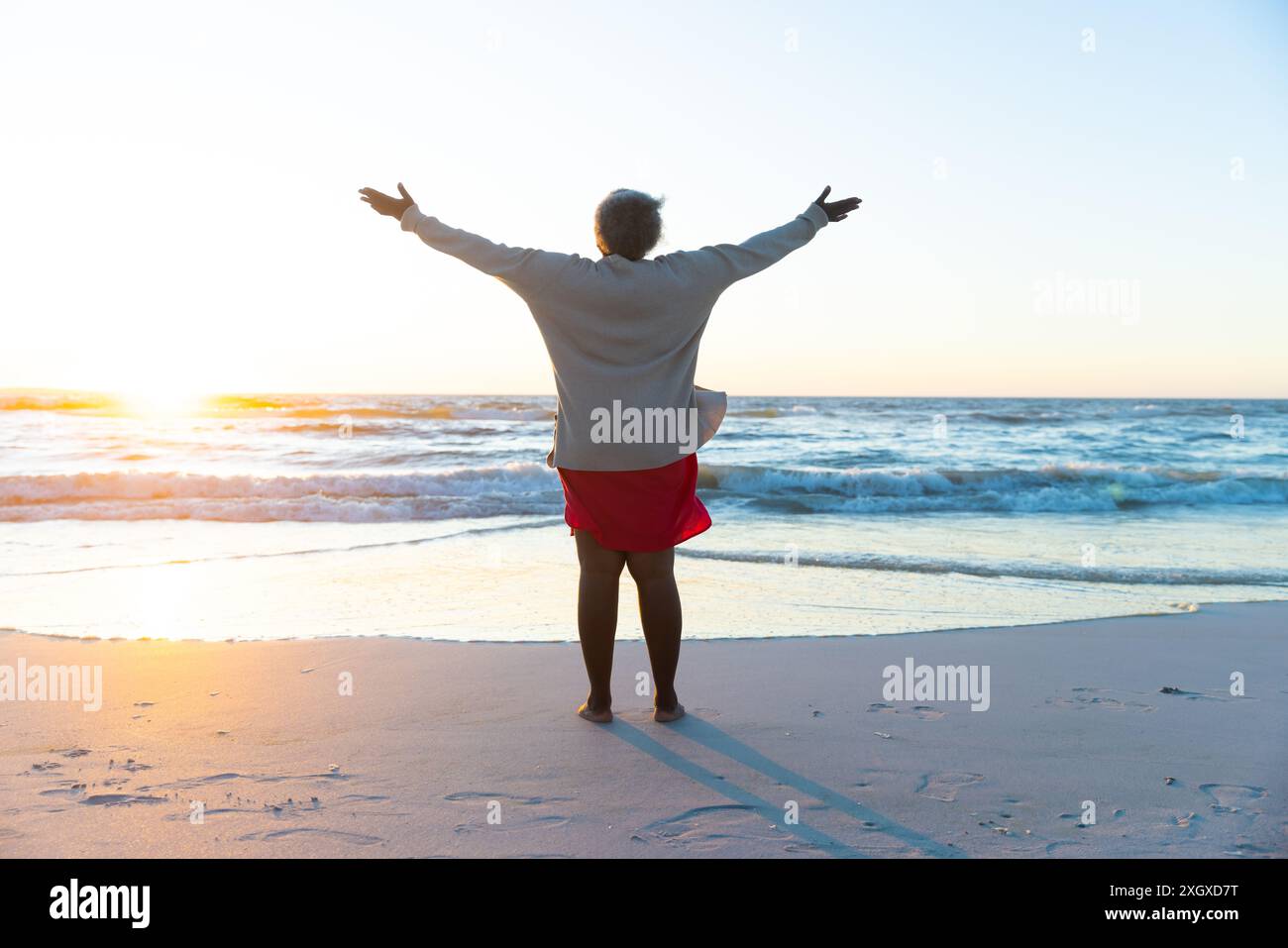 Senior African American woman enjoys a serene beach sunset, with copy ...