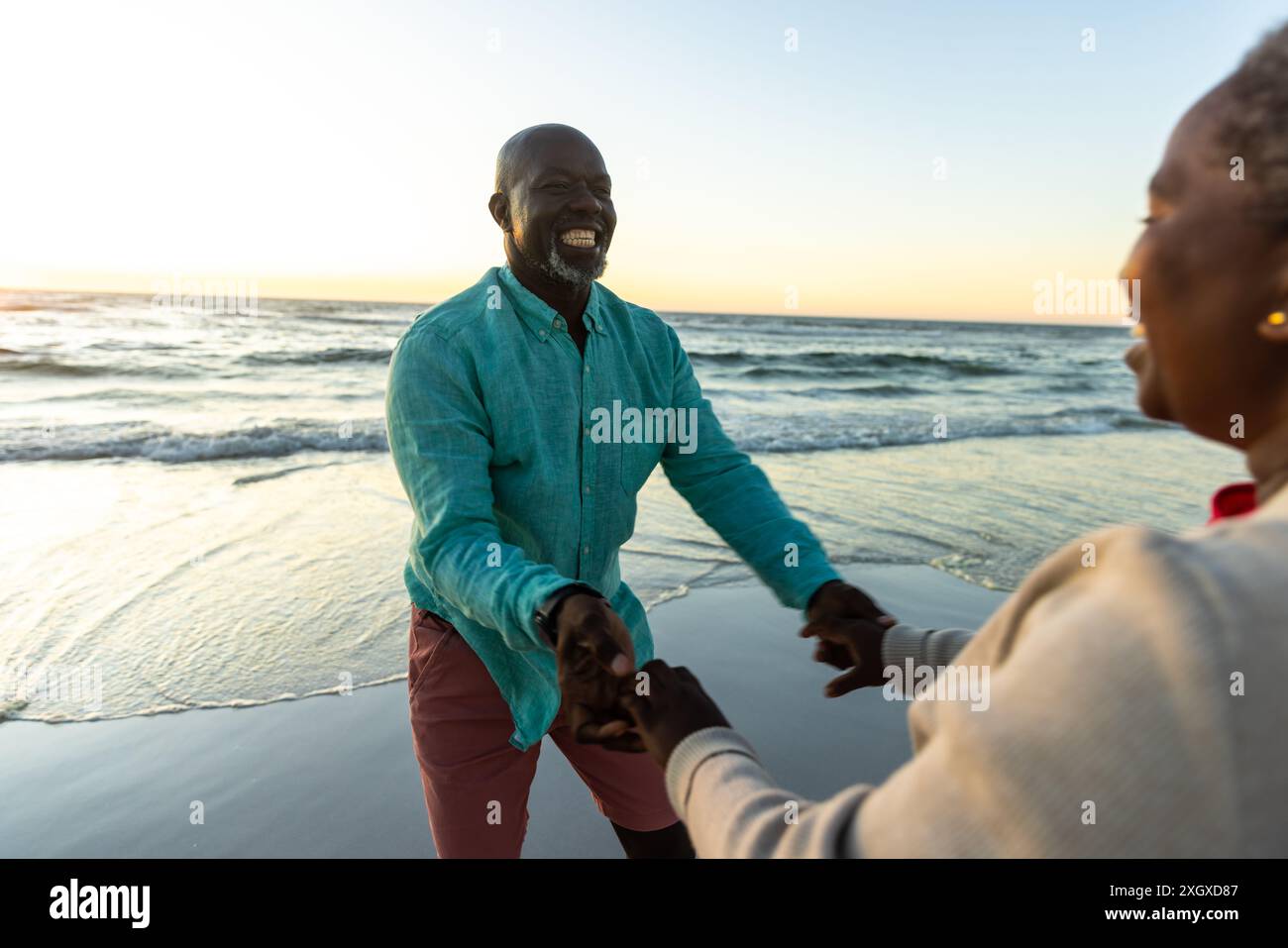 Senior African American couple enjoys a playful moment on the beach ...