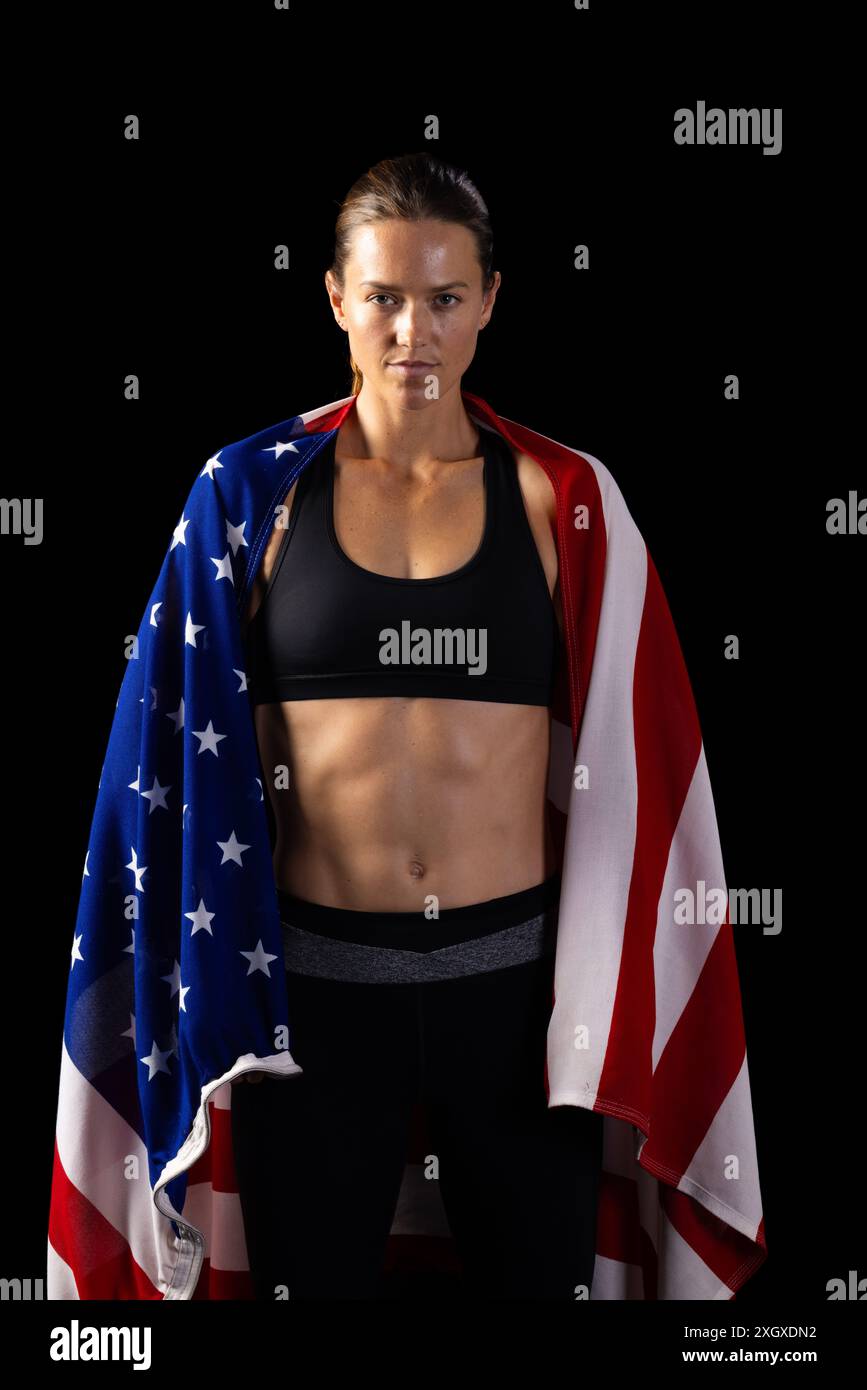 Athletic young Caucasian female athlete draped in an American flag on a ...