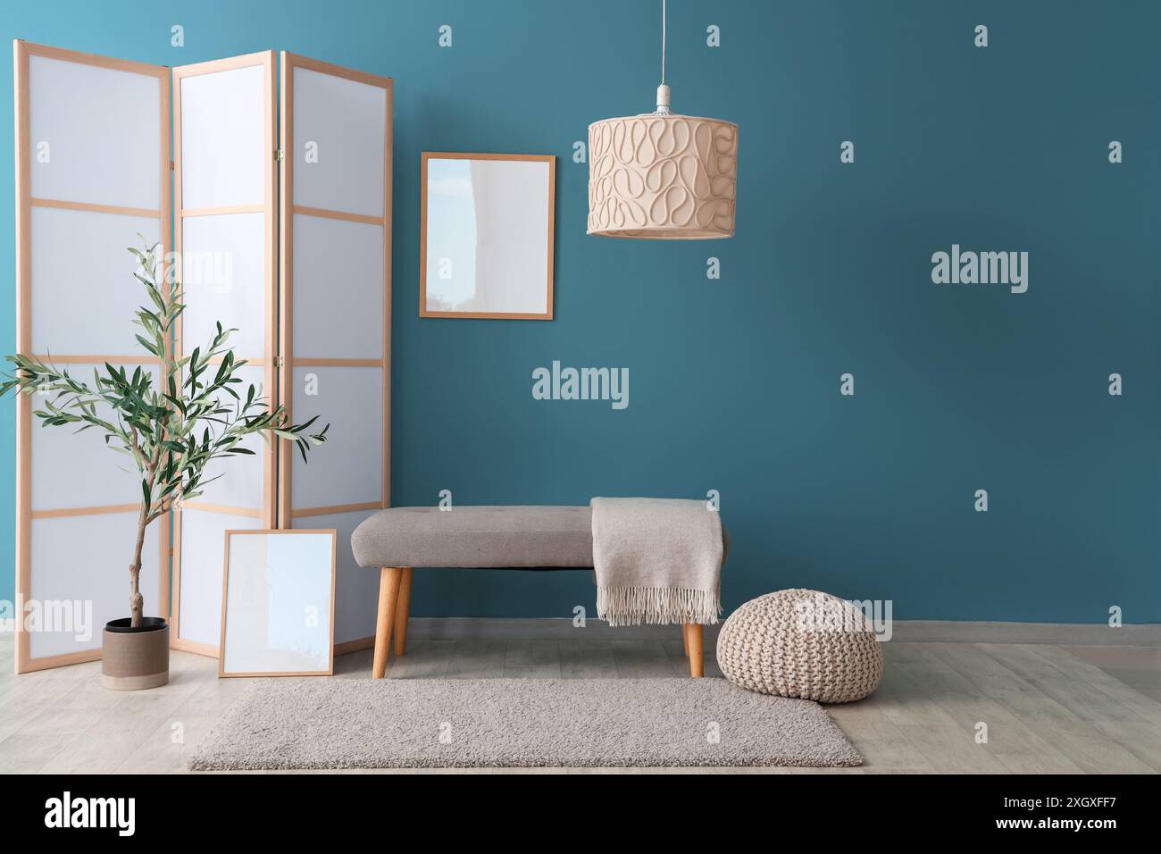 Interior of room with folding screen, bench and houseplant near blue ...