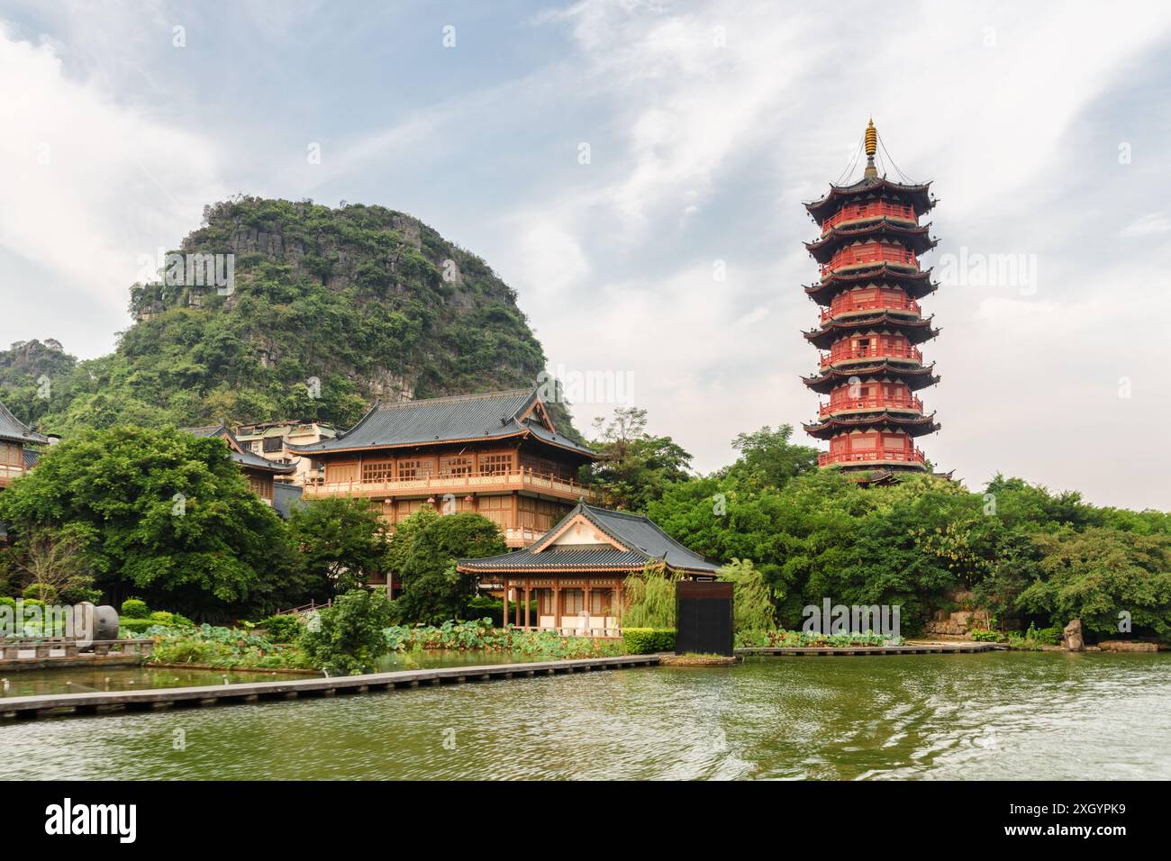 Scenic red pagoda by the Mulong Lake (Wooden Dragon Lake) in Guilin, China. Beautiful wooded karst mountain is visible on blue sky background. Stock Photo