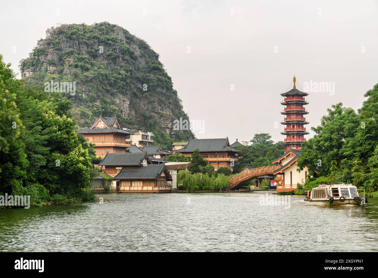 Amazing view of traditional Chinese wooden houses and beautiful red pagoda by lake among green woods and scenic karst mountains in Guilin, China. Stock Photo