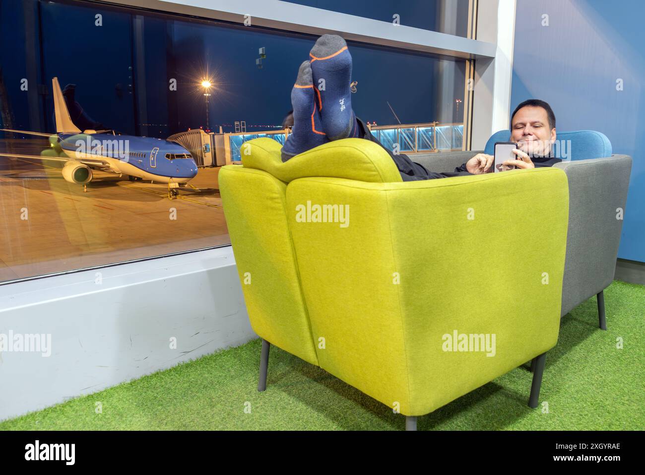 A passenger rests in two displaced chairs for comfort in a night ...
