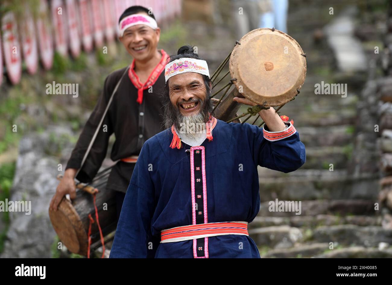 Jinxiu, China's Guangxi Zhuang Autonomous Region. 10th July, 2024. Pan Jinhai (front), an inheritor of the yellow mud drum dance, and Pan Ningyong, an inheritor of yellow mud drum making techniques, carry yellow mud drums on their way to a performance in Jinxiu Yao Autonomous County, south China's Guangxi Zhuang Autonomous Region, July 10, 2024. The yellow mud drum dance of Yao ethnic group was listed as a national intangible cultural heritage. Credit: Lu Boan/Xinhua/Alamy Live News Stock Photo