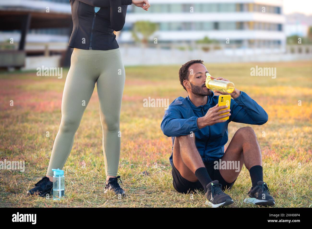 Couple using a social media app on a smartphone while exercising outdoors. Stock Photo