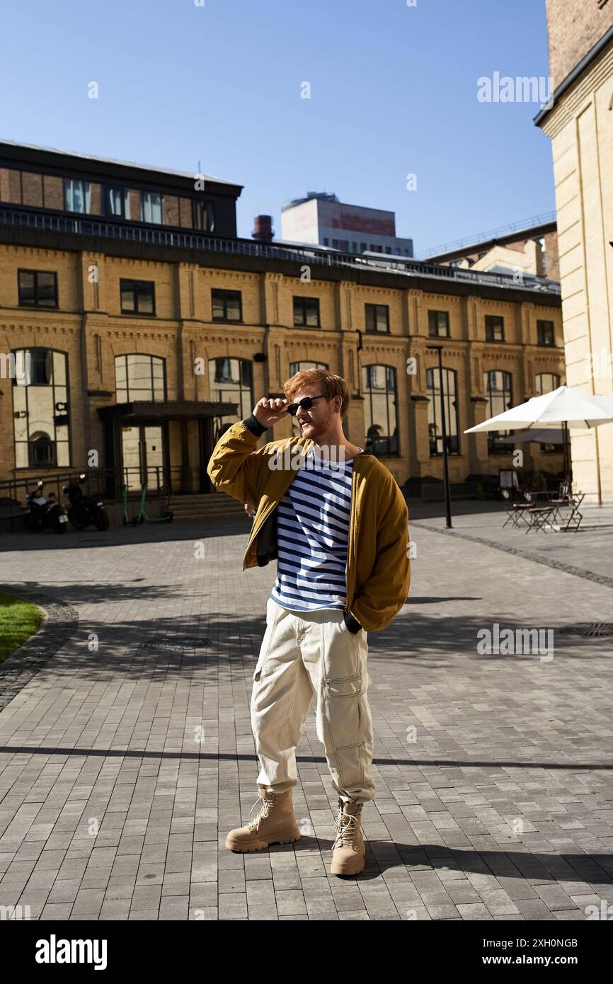 Red-haired man in debonair attire stands in front of building. Stock Photo