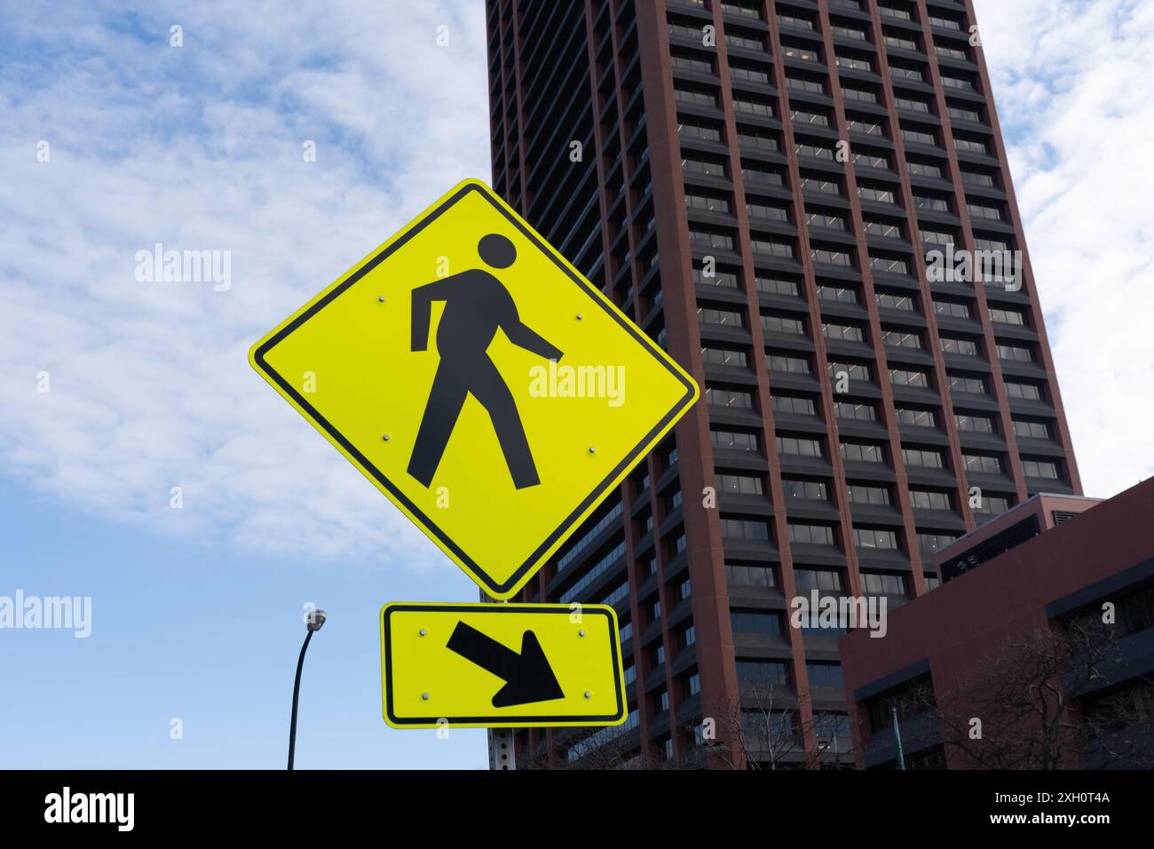 A yellow Pedestrian Crossing Sign with an office building background is shown. Buffalo, New York,  USA. Stock Photo