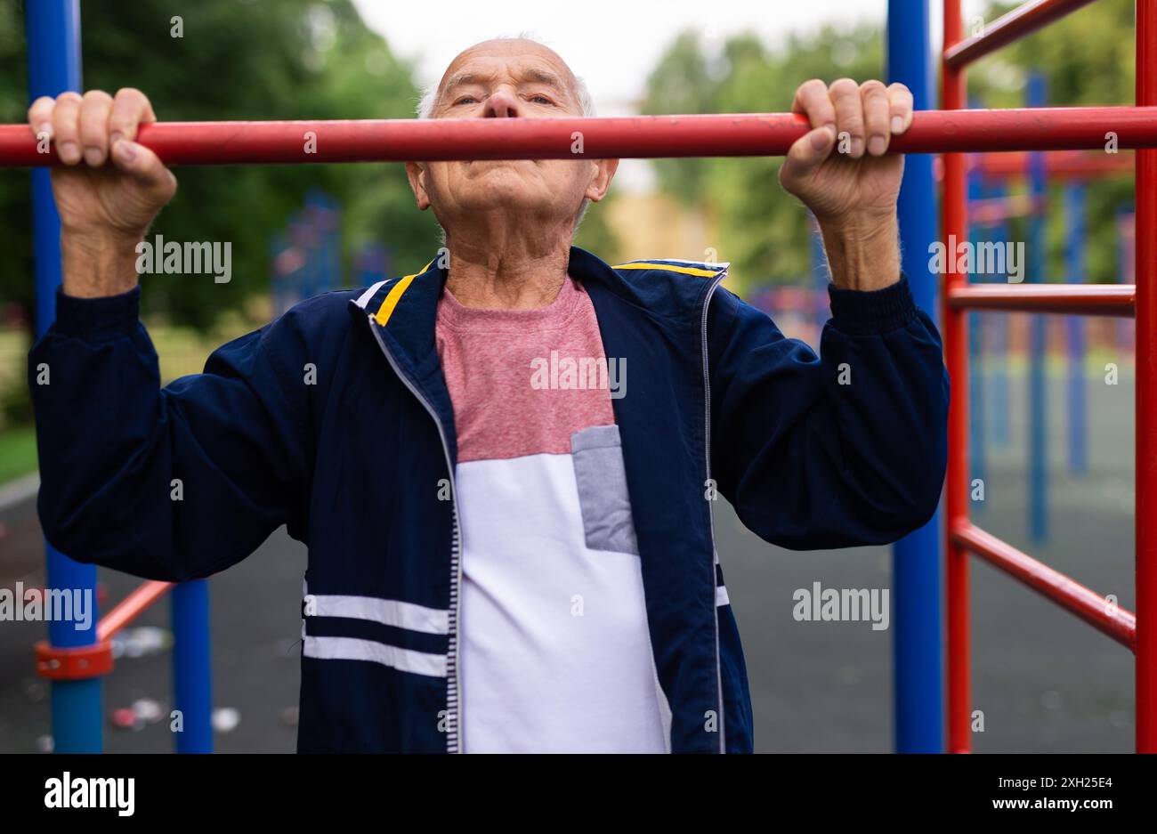Sportive old man doing pull-ups outdoors Stock Photo