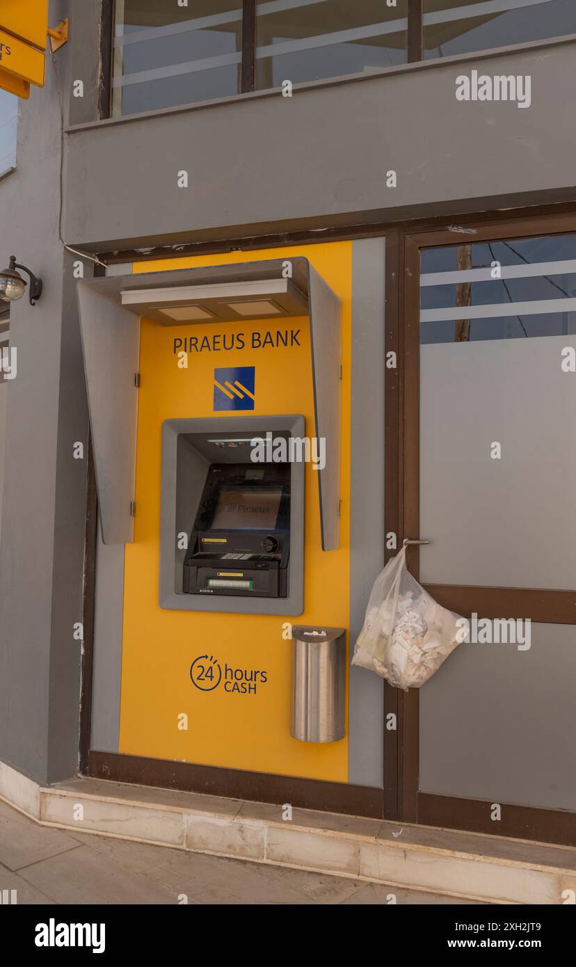 Crete, Greece, Europe.  12.06.2024. Cash dispensing machine with plastic bag for disposal of receipts outside a Greek Bank in Crete, Greece. Stock Photo
