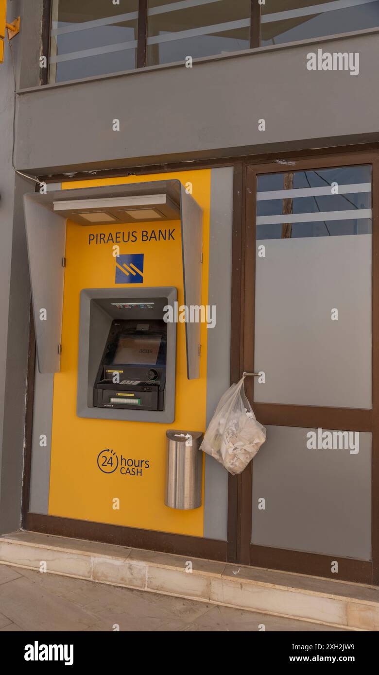 Crete, Greece, Europe.  12.06.2024. Cash dispensing machine with plastic bag for disposal of receipts outside a Greek Bank in Crete, Greece. Stock Photo