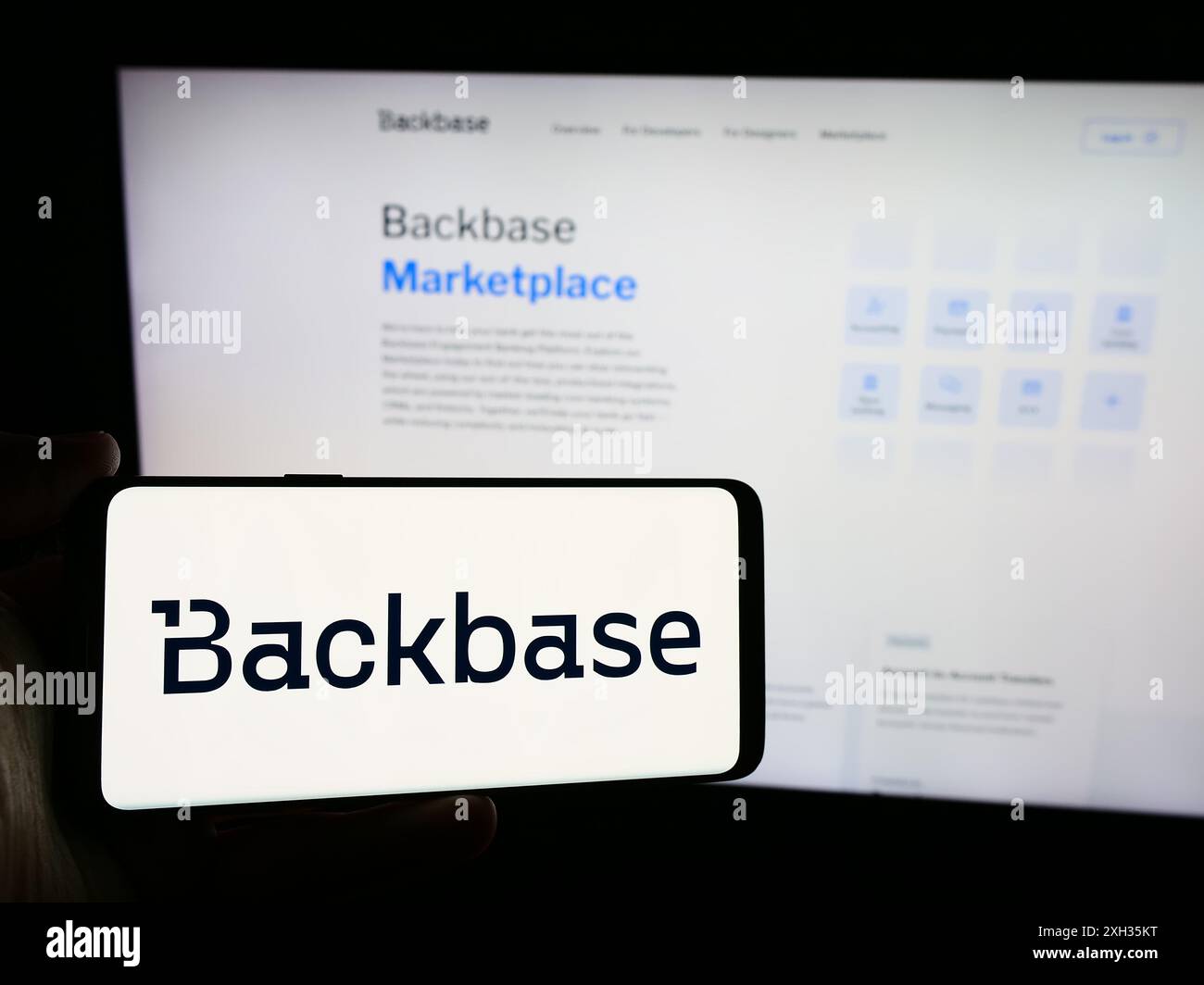 Person holding smartphone with logo of Dutch fintech company Backbase B.V. in front of website. Focus on phone display. Stock Photo