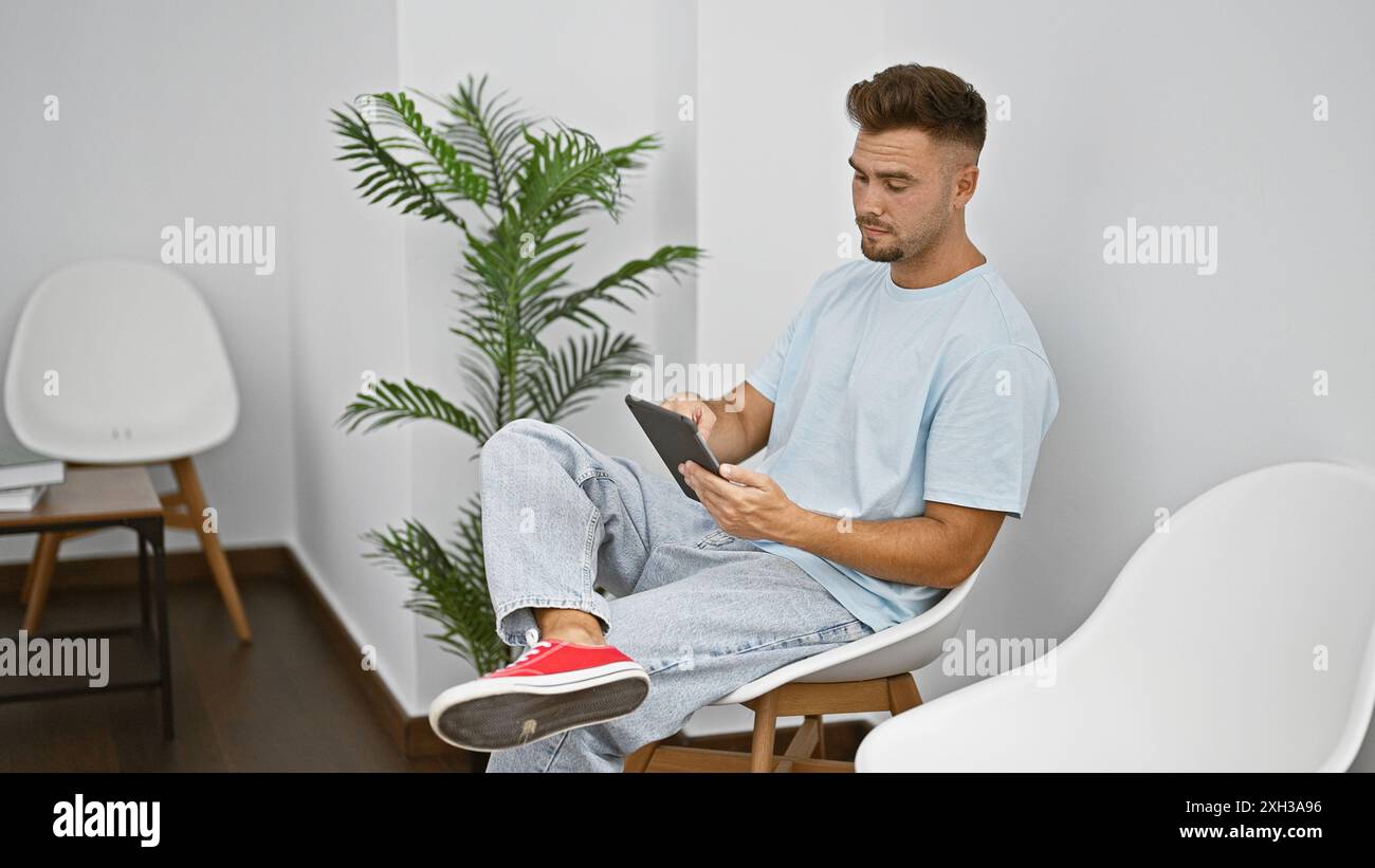 Handsome hispanic man using tablet in a modern waiting room. Stock Photo