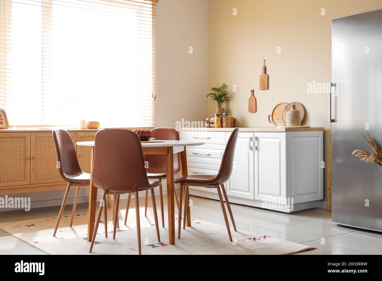 Interior of light kitchen with stylish fridge, white counter and dining ...