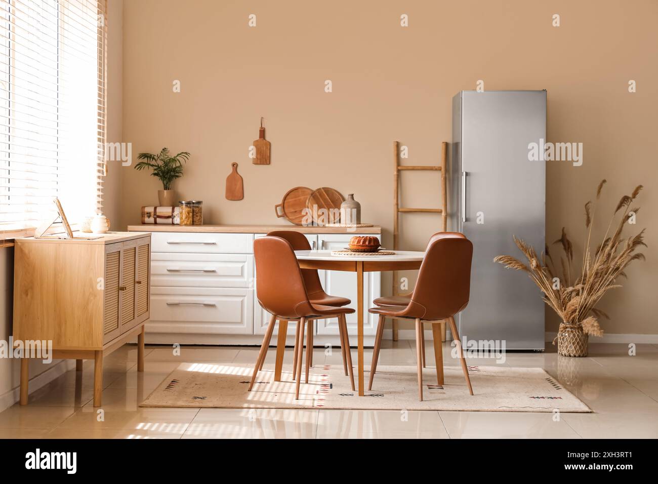 Interior of light kitchen with stylish fridge, white counter and dining ...