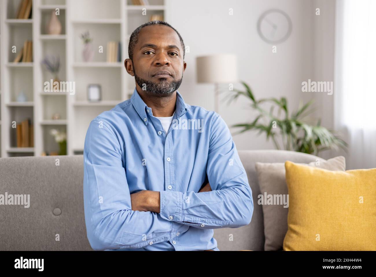 Confident Man Sitting On Couch With Arms Crossed In Modern Living Room Confident man sitting on couch with arms crossed in modern living room