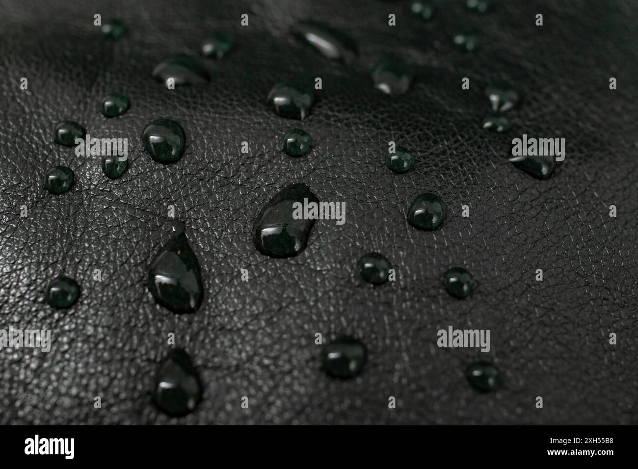 Round water drops on black leather texture, side view, soft focus Stock Photo