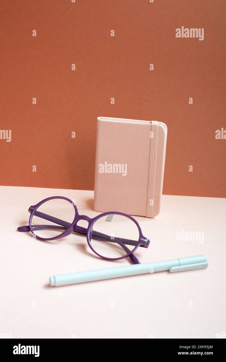 Diary notebook, pen, eyeglasses on pink desk. red background Stock Photo