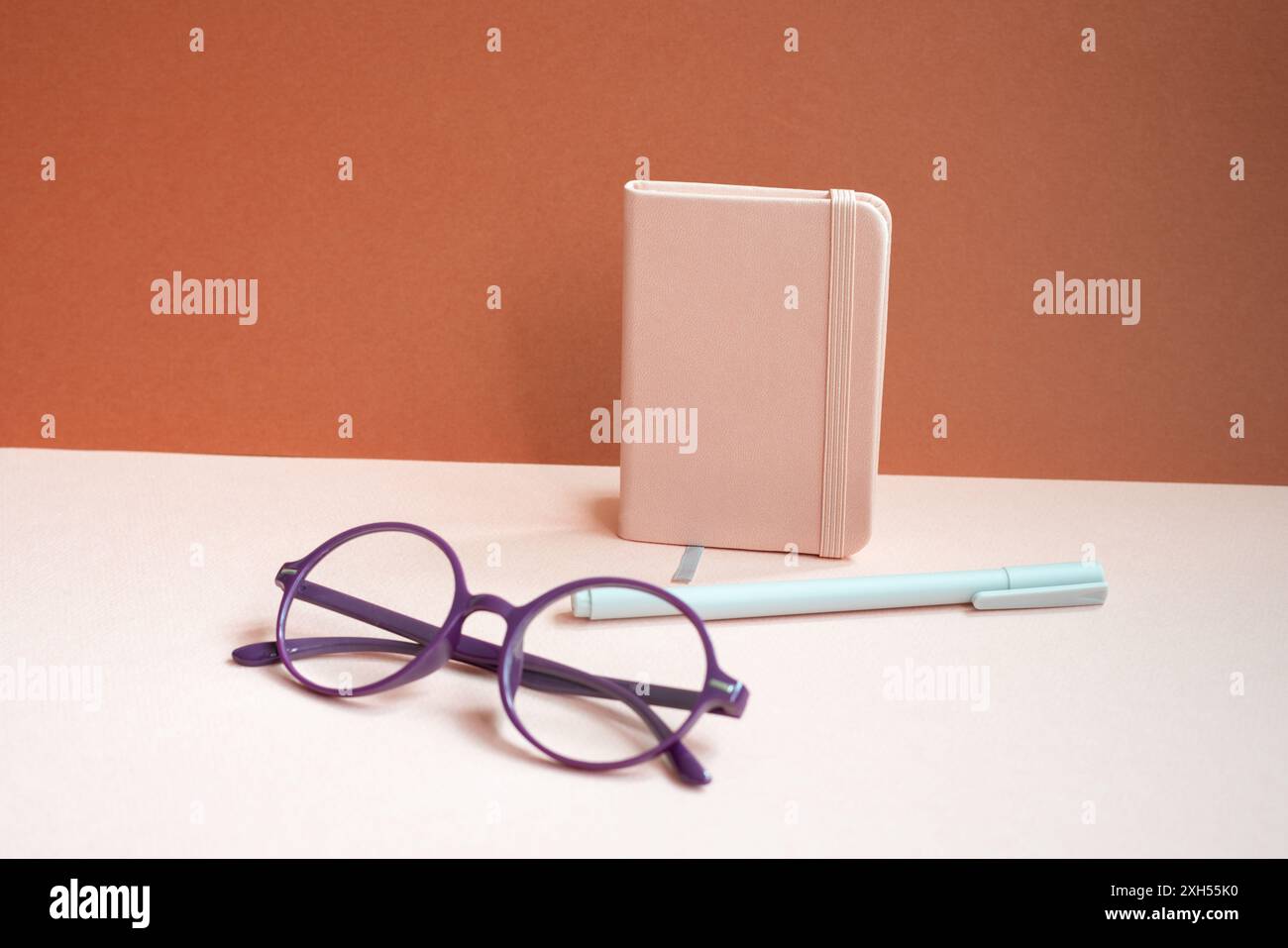Diary notebook, pen, eyeglasses on pink desk. red background Stock Photo