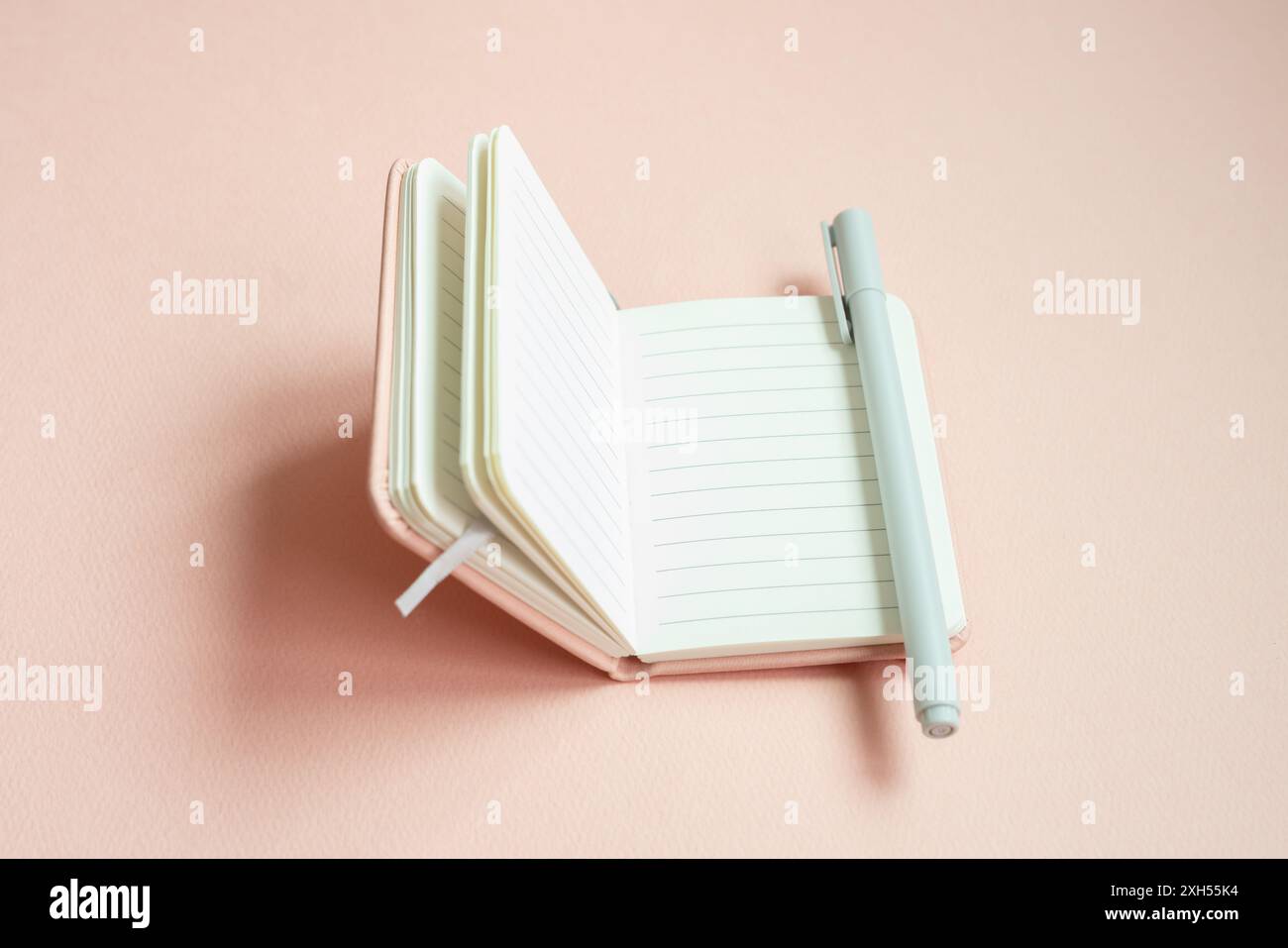 Open lined notebook and pen on pink desk background Stock Photo