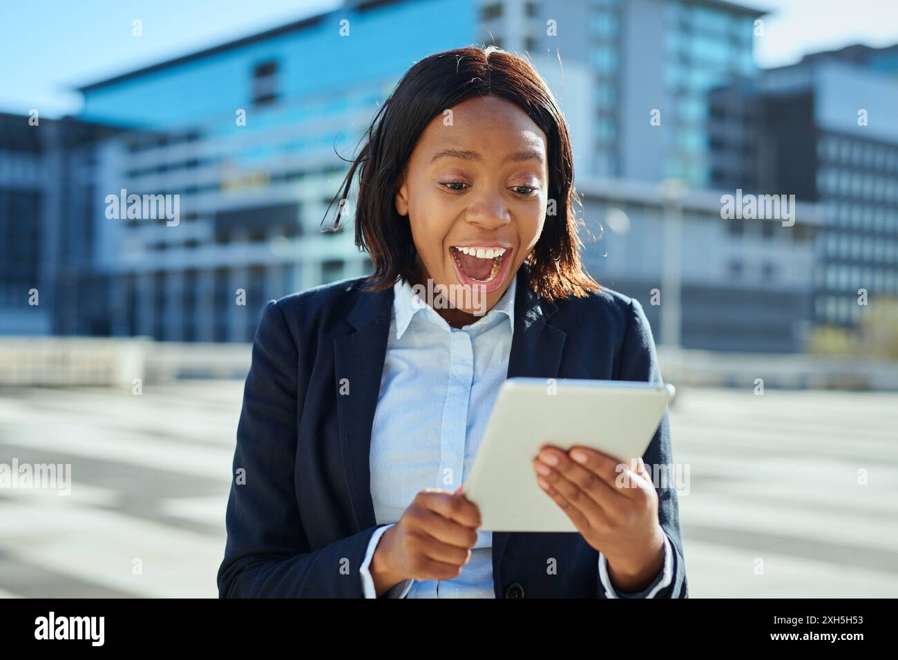 Excited Young Female Entrepreneur Using Tablet in Urban Environment Stock Photo