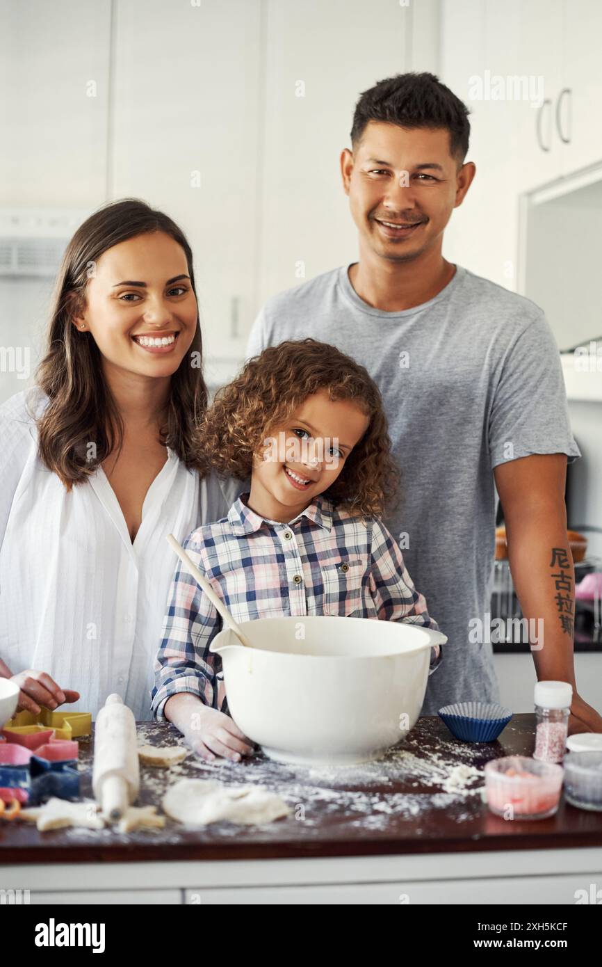 Happy, baking and portrait of family in kitchen for preparing cookies, biscuits or cupcakes at home. Smile, flour and girl kid learning dessert recipe Stock Photo