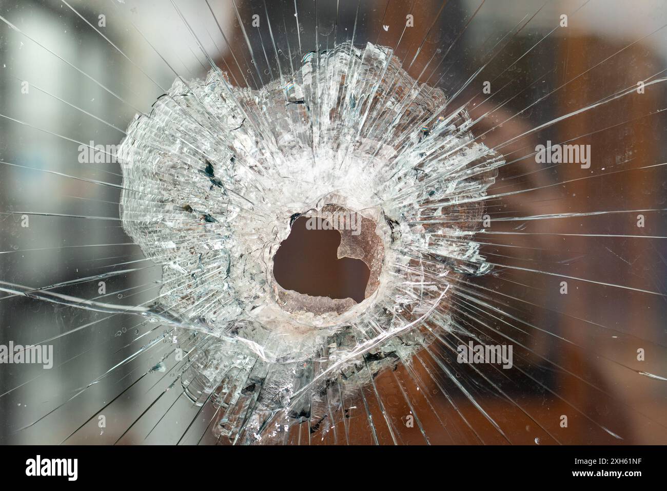 Close-up of shattered glass with a central bullet hole impact Stock Photo
