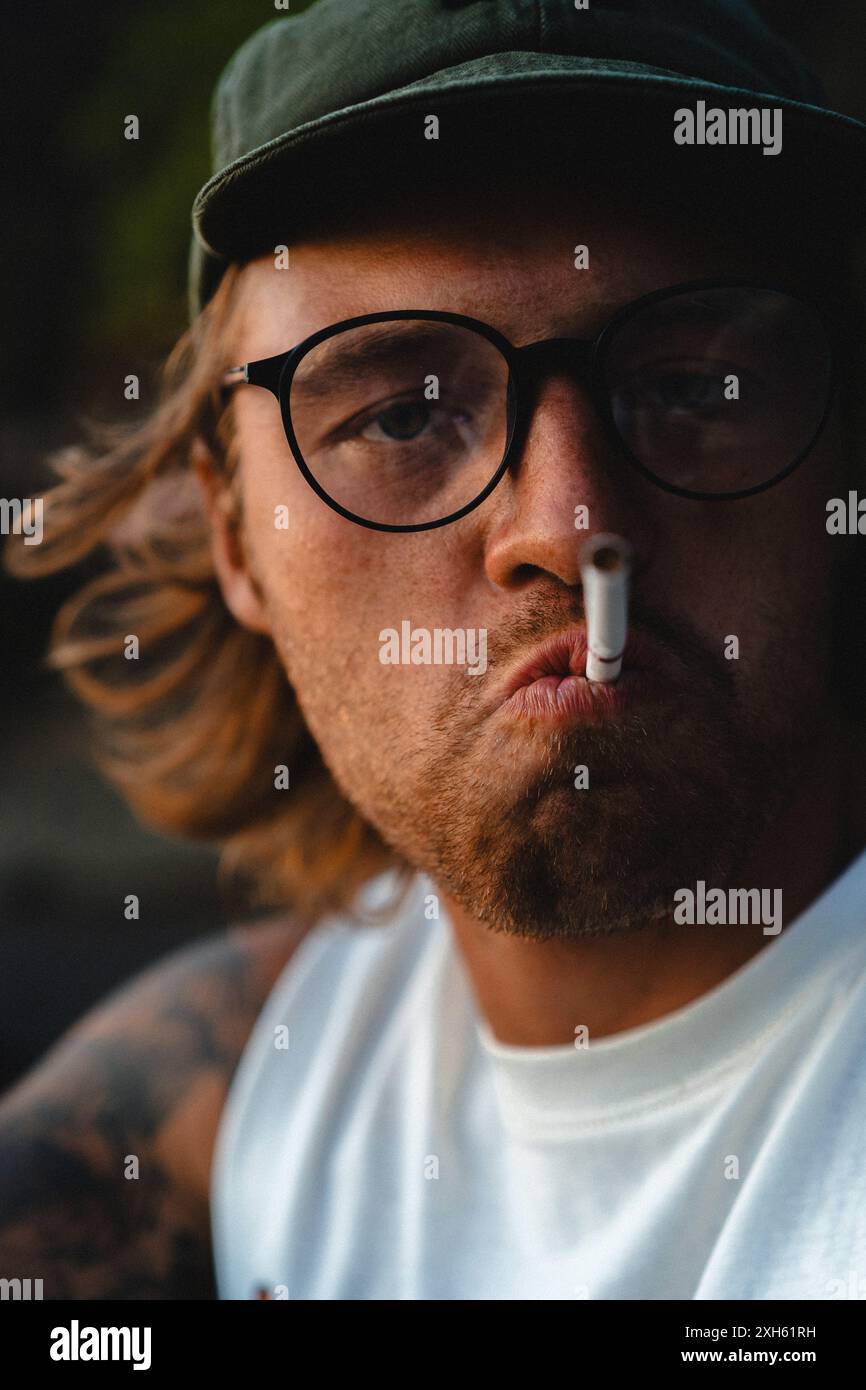 A young man lights a cigarette. Stock Photo