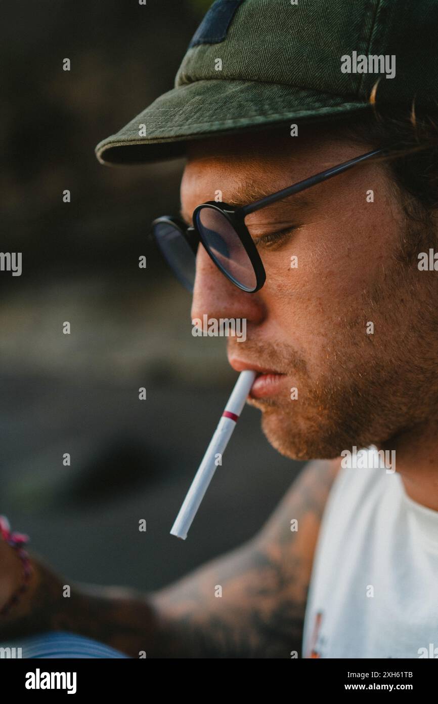 A young man lights a cigarette. Stock Photo