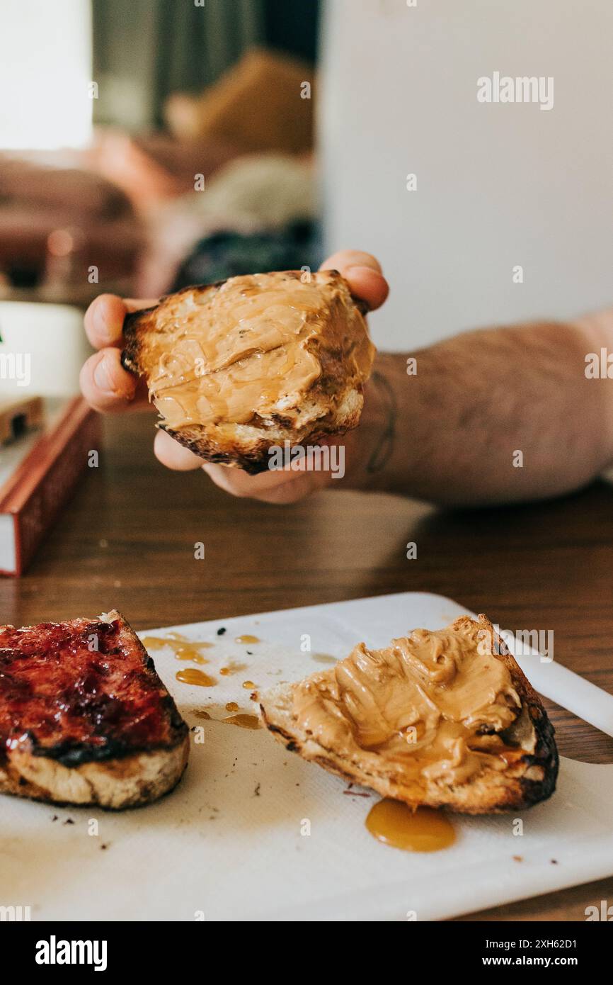 Man holds homemade sourdough toast with peanut butter and honey Stock Photo
