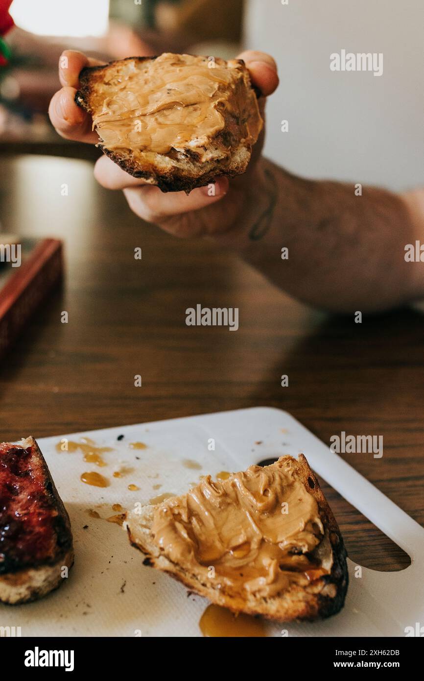 Man holds homemade sourdough toast with peanut butter and honey Stock Photo