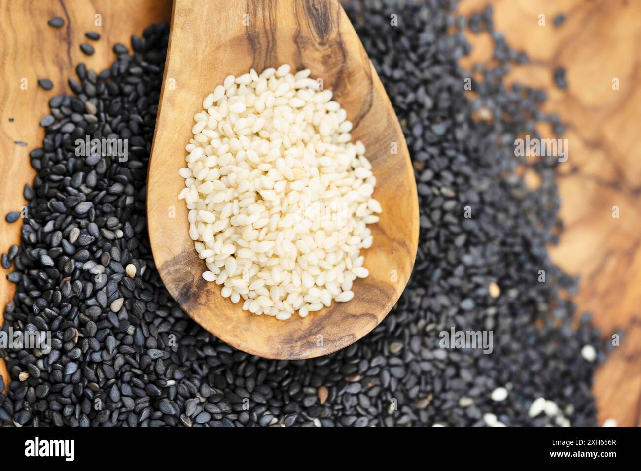 sesamum, sesame (Sesamum indicum), peeled and unpeeled sesame seeds with wooden spoon Stock Photo