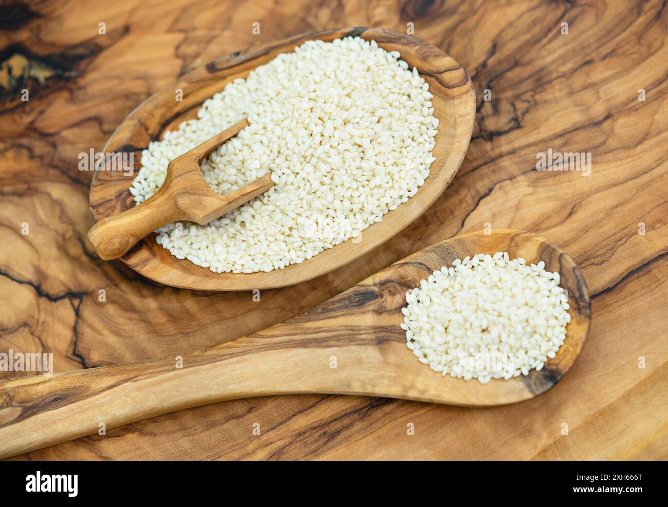 sesamum, sesame (Sesamum indicum), peeled sesame seeds with wooden scoop and wooden spoon Stock Photo