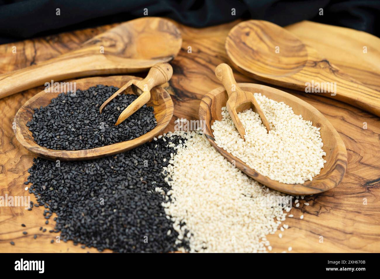 sesamum, sesame (Sesamum indicum), peeled and unpeeled sesame seeds with wooden scoops and wooden spoons Stock Photo