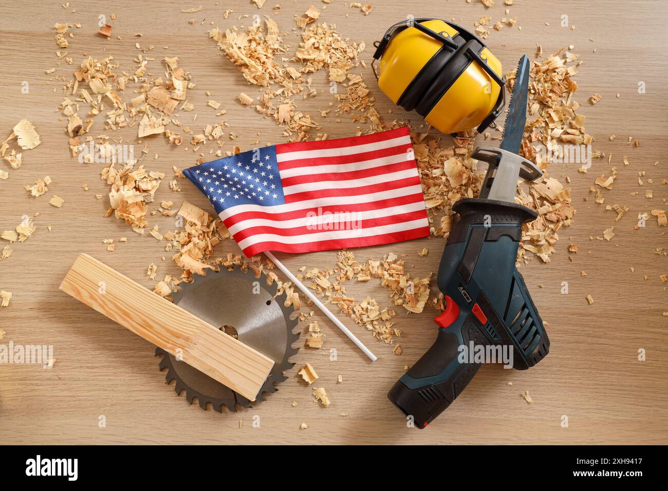 Reciprocating saw, USA flag, Circular-saw disk and sawdust on wooden table. Labor Day celebration Stock Photo