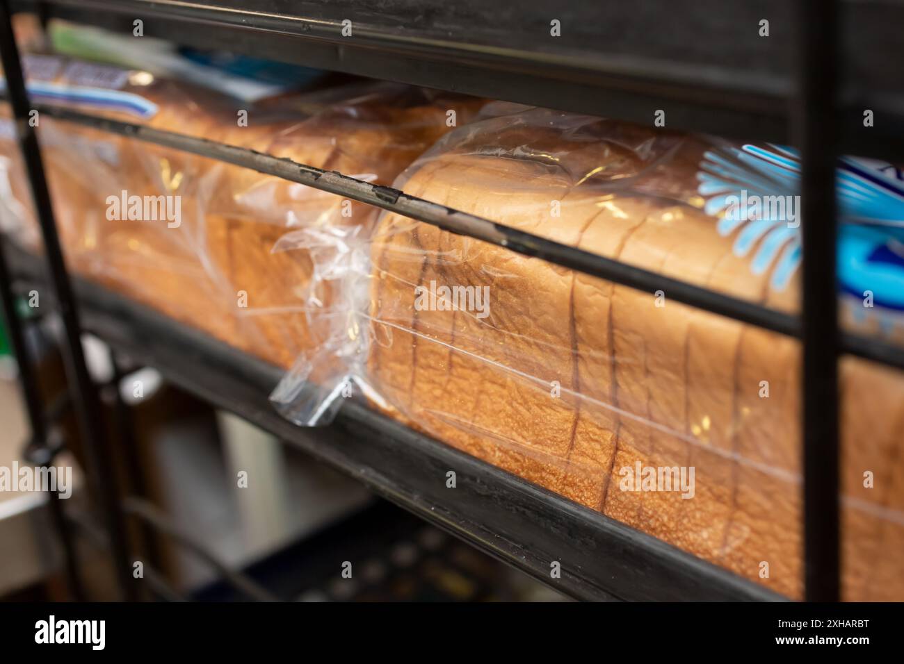 A view of several bags of sliced white bread, on a tray rack, in a restaurant kitchen setting. Stock Photo