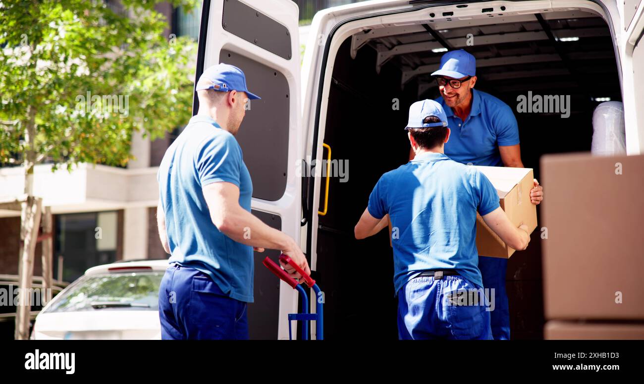 The experienced courier team is unloading cardboard boxes from the van, providing moving services for the local hardware store. Stock Photo