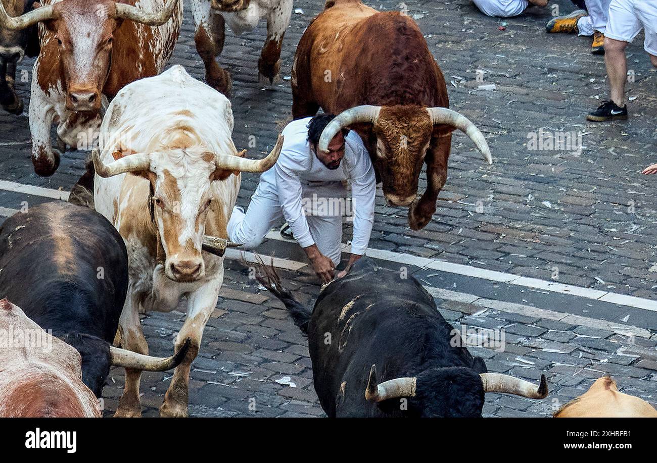 Several runners run in front of the bulls through the streets of Pamplona during the first running of the bulls at the San Fermín 2024 festivities, led by La Palmosilla Sancho. The Pamplona bull run is a tradition with medieval origins. The run takes place early in the morning, before the bull fights. Hundreds of daredevils wearing white shirts and red scarves race six bulls through the streets of the city. The event was immortalised by writer Ernest Hemingway in his 1926 book 'The Sun Also Rises'. Pamplona's festival of San Fermín is a week-long celebration which starts at noon on July 6 and Stock Photo