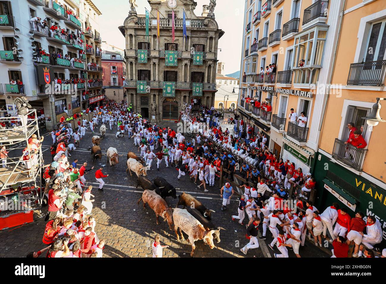 July 7, 2024, Pamplona, Spain: Several runners run in front of the bulls through the streets of Pamplona during the first running of the bulls at the San FermÃ-n 2024 festivities, led by La Palmosilla Sancho. The Pamplona bull run is a tradition with medieval origins. The run takes place early in the morning, before the bull fights. Hundreds of daredevils wearing white shirts and red scarves race six bulls through the streets of the city. The event was immortalised by writer Ernest Hemingway in his 1926 book ''The Sun Also Rises''. Pamplona's festival of San FermÃ-n is a week-long celebration Stock Photo