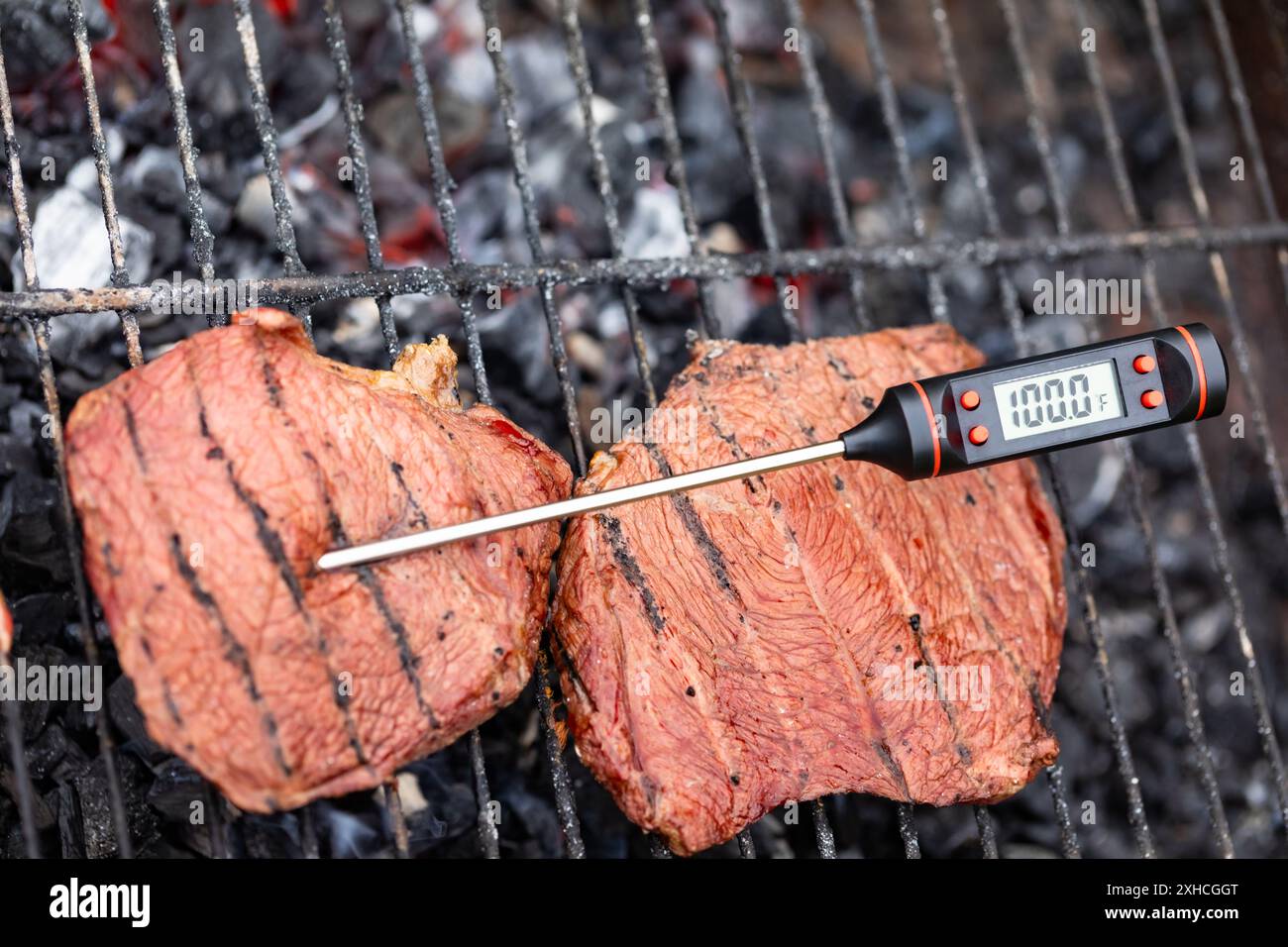 Closeup shot of undercooked grilled steak on barbecue with digital