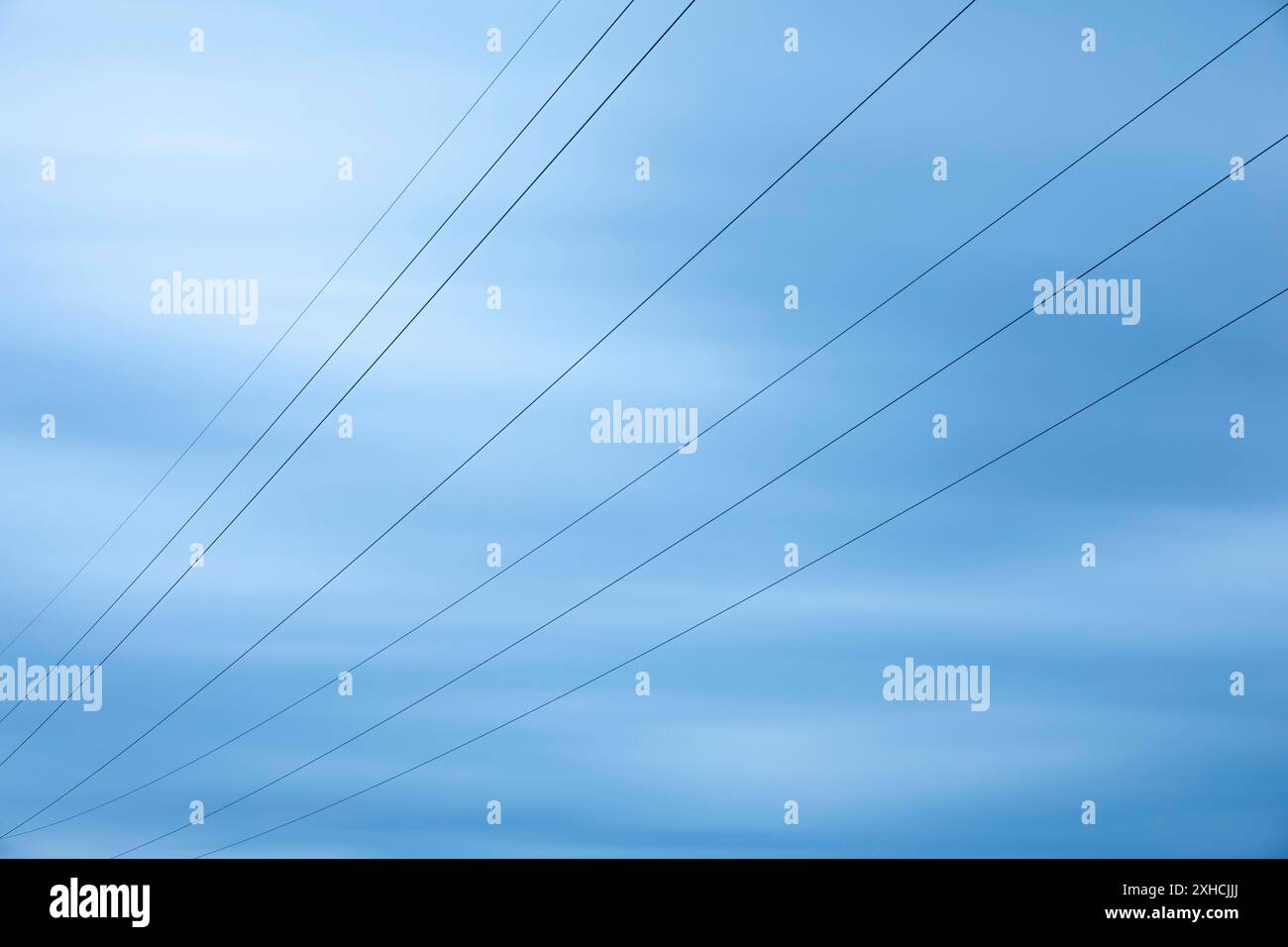 Power lines in front of a blue sky, long exposure Stock Photo - Alamy