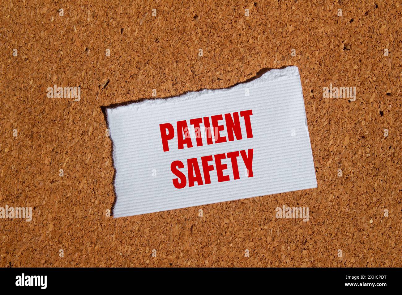 Patient safety words written on ripped white paper piece with brown ...