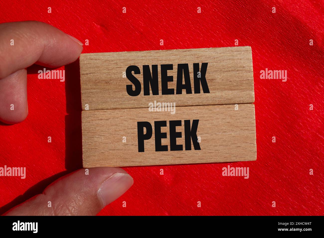 Sneak peek words written on wooden blocks with red background. Conceptual sneak peek symbol. Copy space. Stock Photo