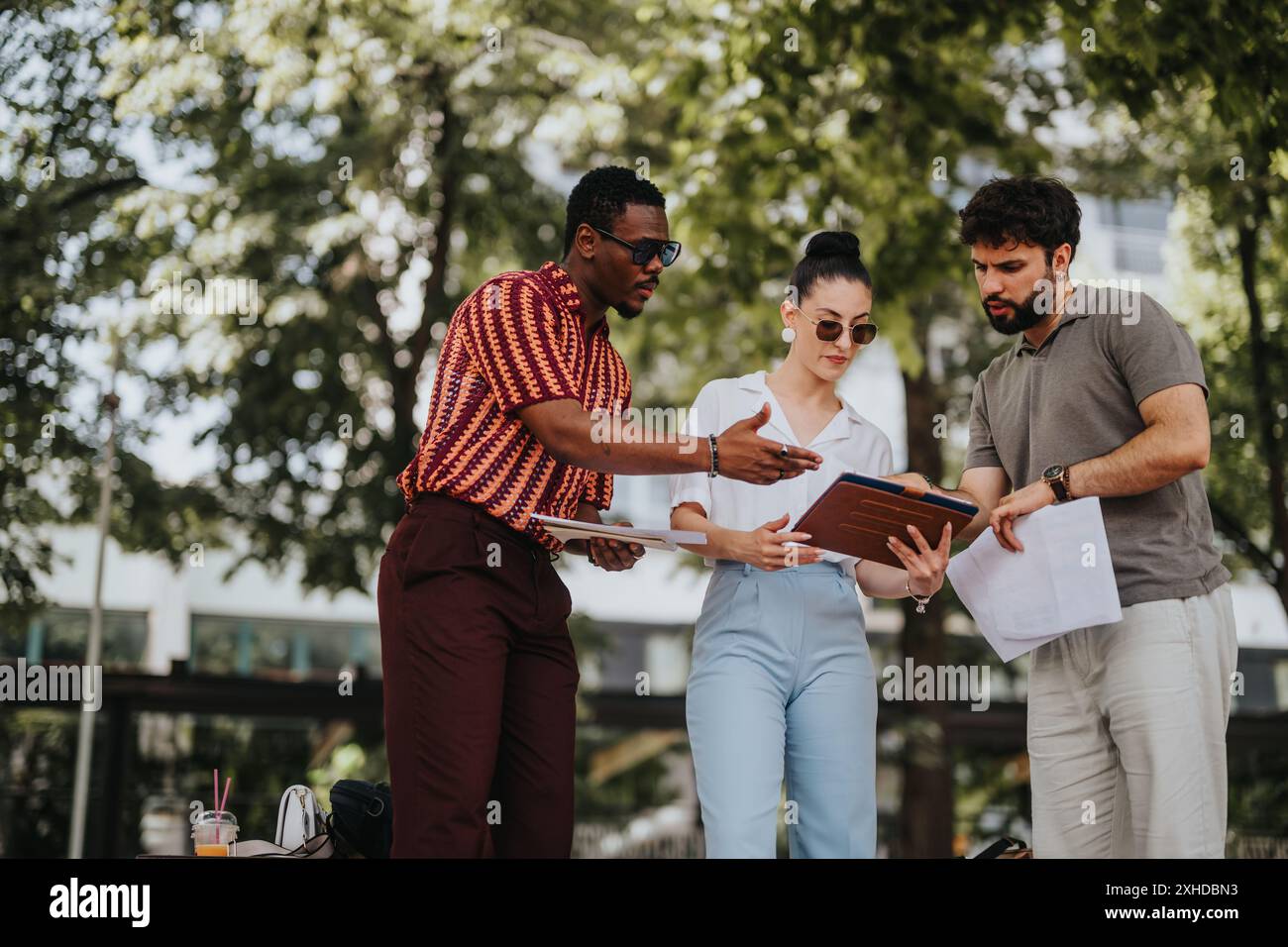 Diverse team collaborating on project in outdoor setting, discussing documents and sharing ideas Stock Photo