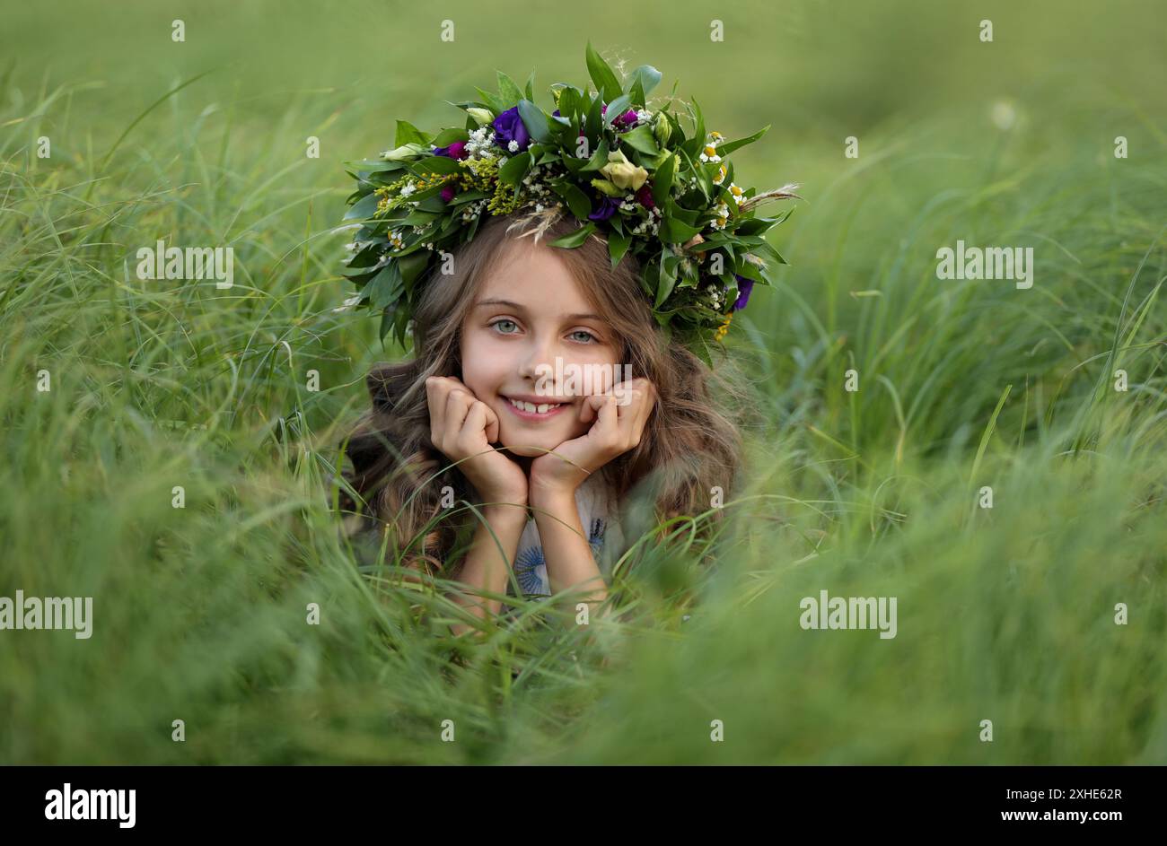 Cute little girl wearing wreath made of beautiful flowers in field ...
