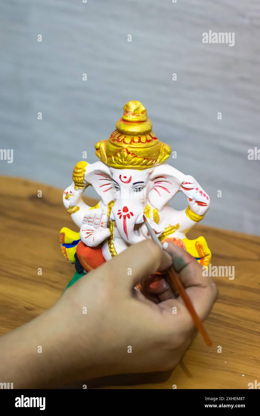 devotee coloring the hindu god ganpati idol on the occasion of ganesh chaturthi Stock Photo
