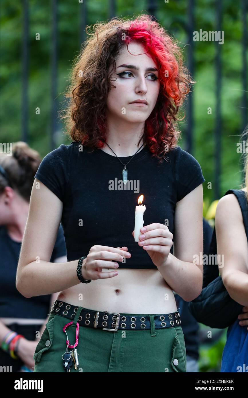 University Park, United States. 13th July, 2024. A person holds a candle  during a vigil for Pauly Likens at the Allen Street Gates of Penn State  University in State College, Pa. on, image size:866x1390