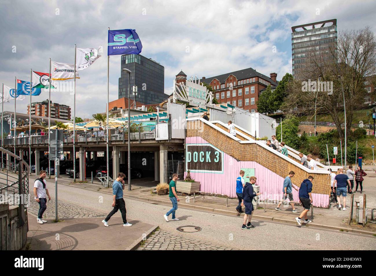 Group of men walking to Dock 3 Beach Club at Bei den St. Pauli-Landungsbrücken or St. Pauli Piers in Hamburg, Germany Stock Photo